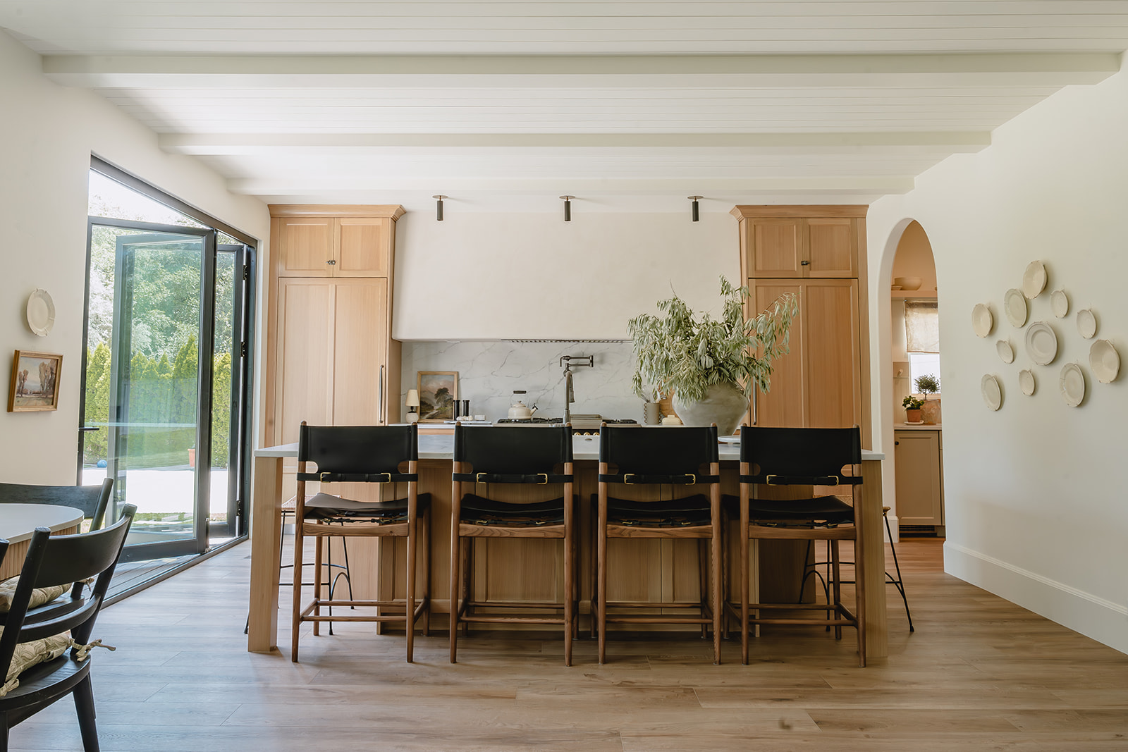 Kitchen island with black leather counter stools and plaster hood