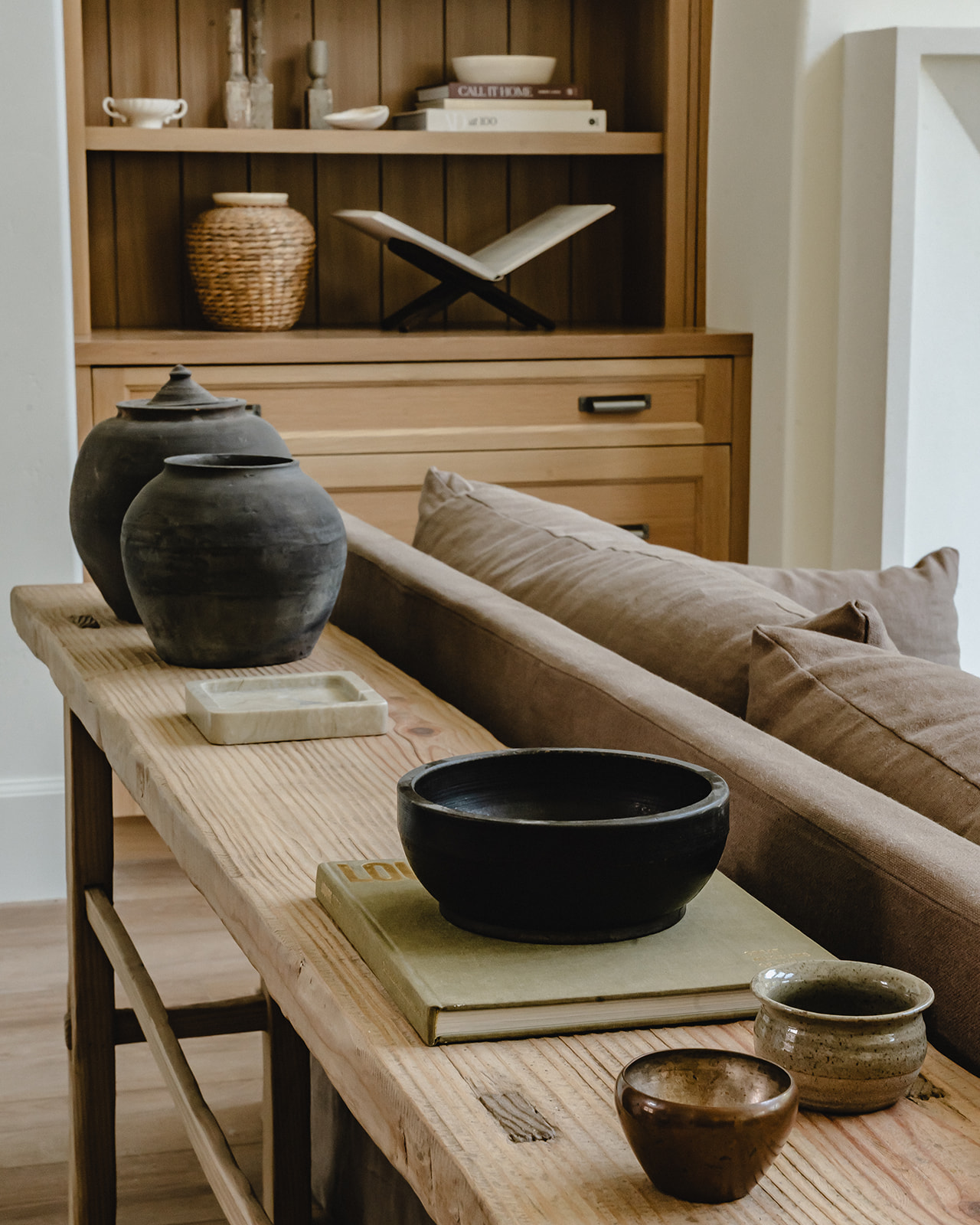 Console table behind sofa with collected pottery and books