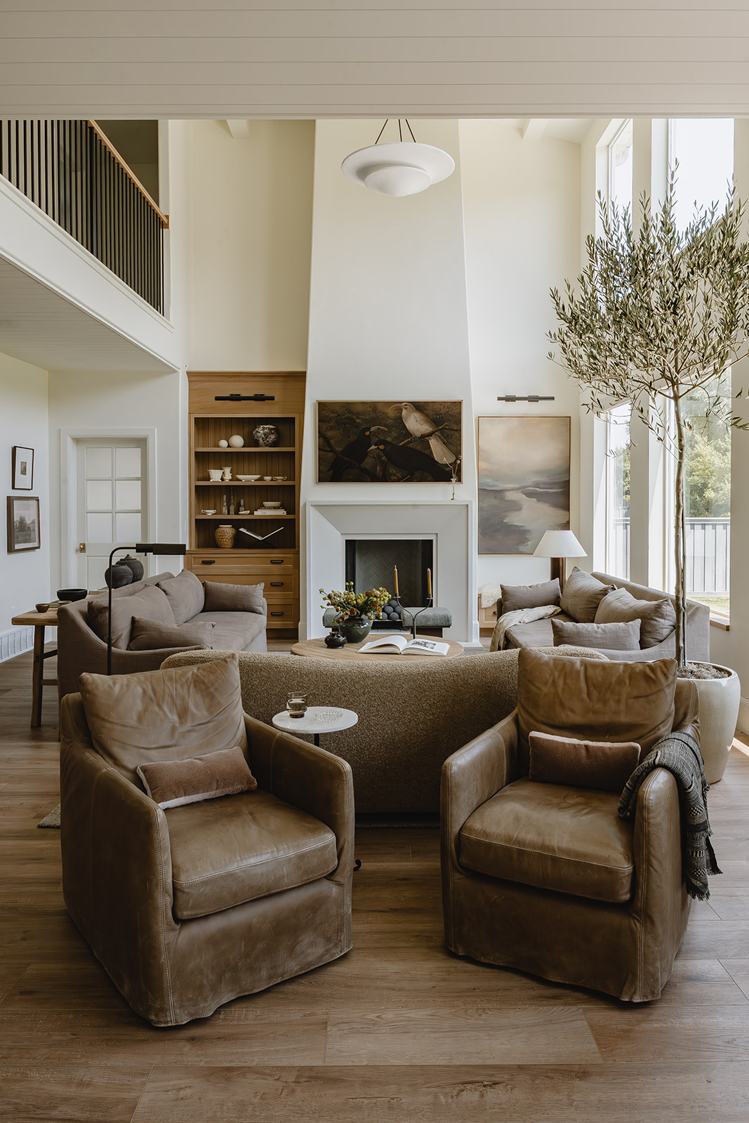 Two-story living room with fireplace, leather chairs and olive tree