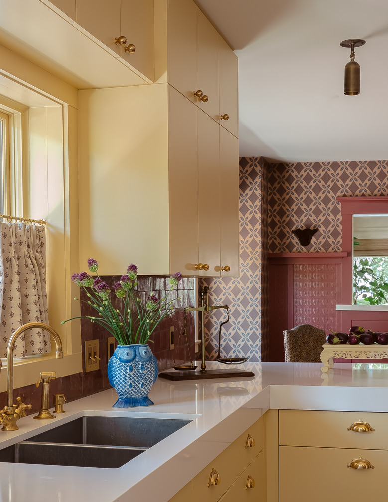 Kitchen corner with blue owl vase, brass fixtures, and patterned wallpaper beyond