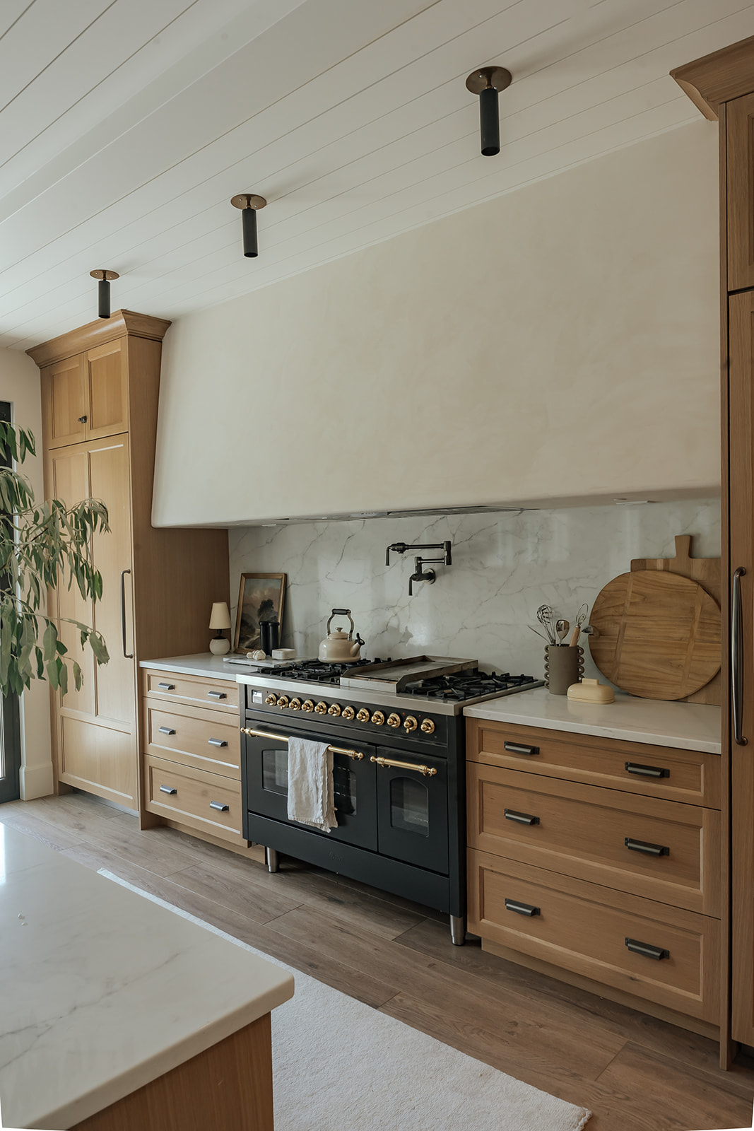 Range wall with marble slab backsplash and white oak cabinetry