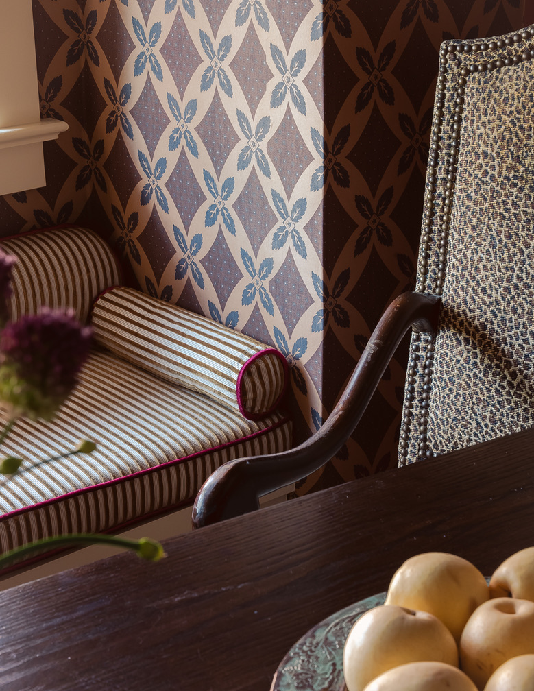 Detail of striped chaise against graphic blue and brown wallpaper