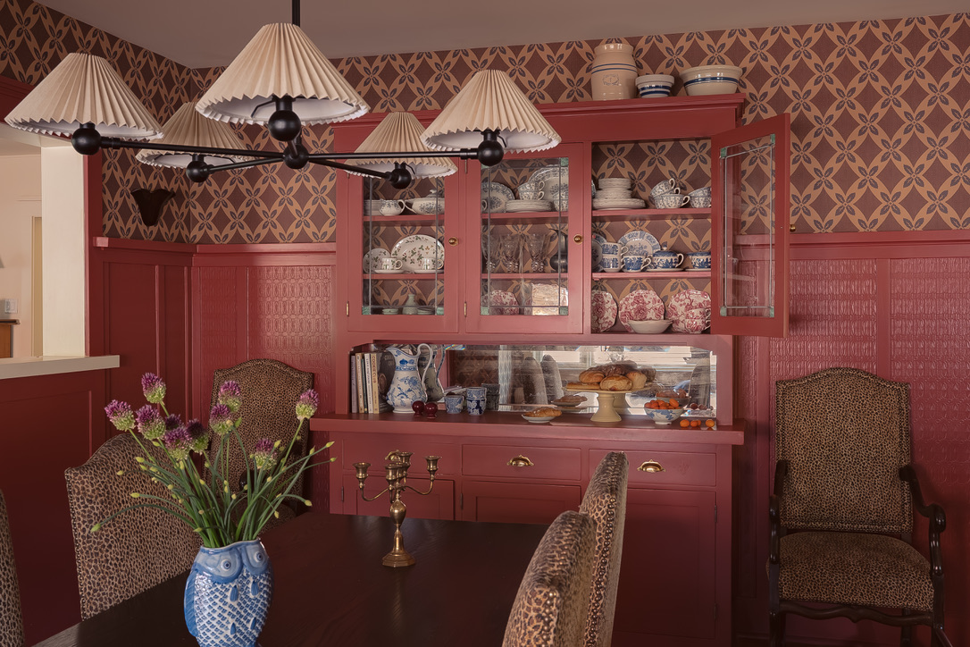 Rose-red built-in china cabinet with patterned wallpaper in the dining room