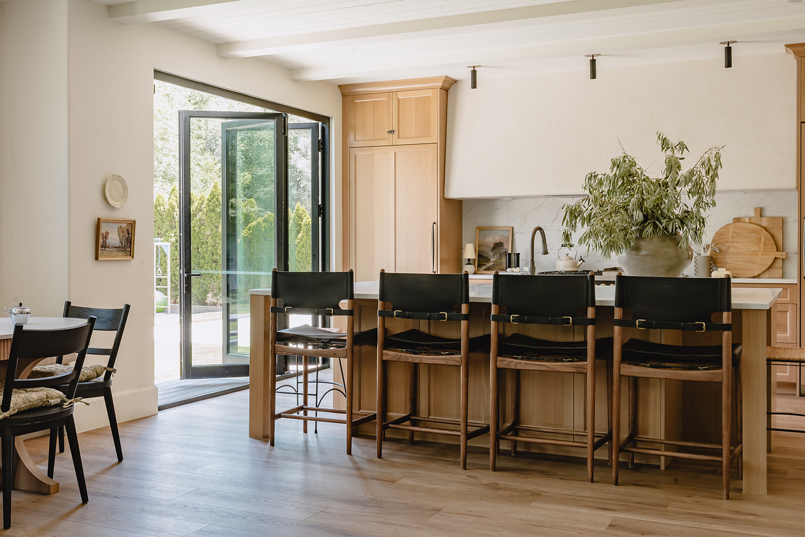 Open kitchen with leather counter stools and folding glass doors to garden