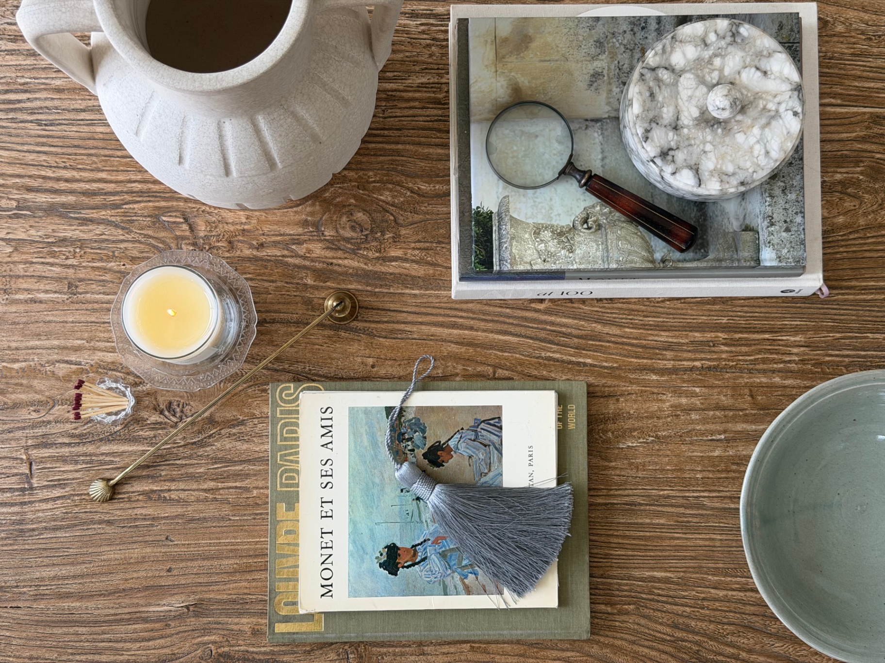 Styled tabletop with Monet book, candle, and ceramic vessels